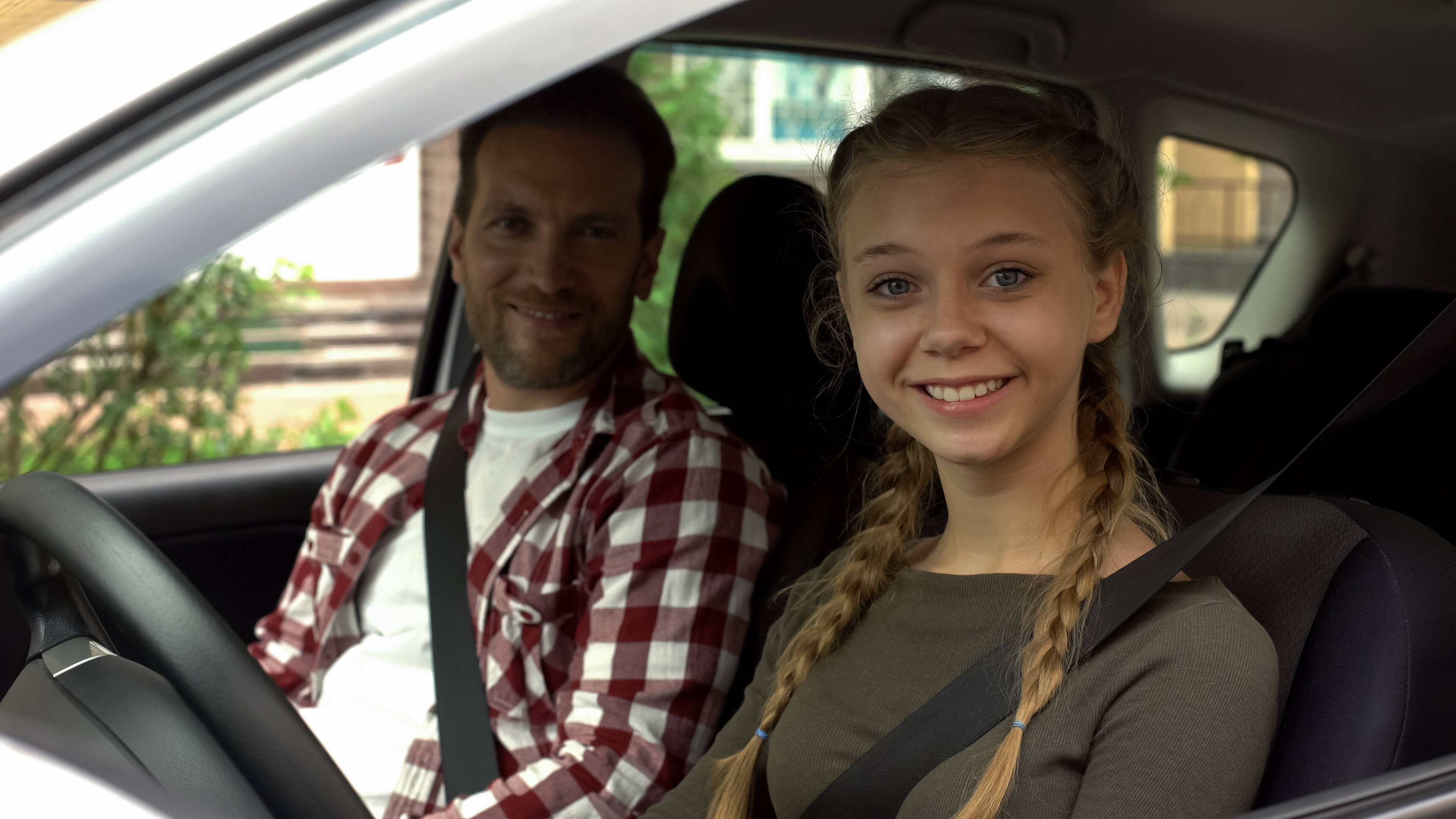 A happy girl behind the wheel with an instructor